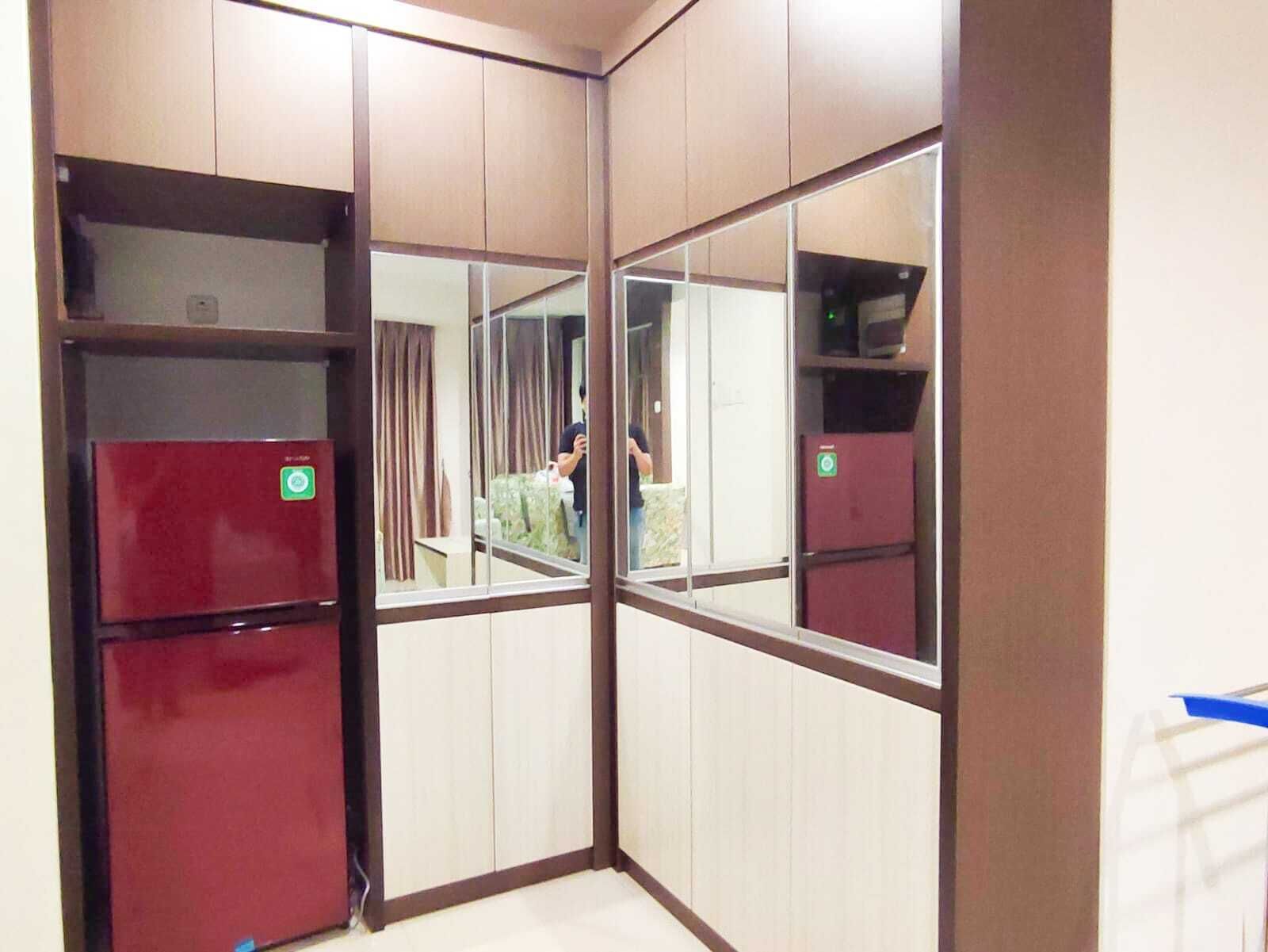 Habitación de esquina con paredes espejadas, un refrigerador rojo y un ventanal pequeño.