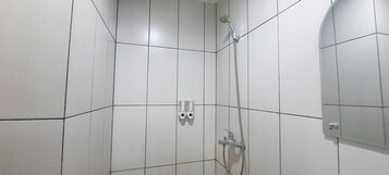 A shower area with white tiled walls and a shower head.