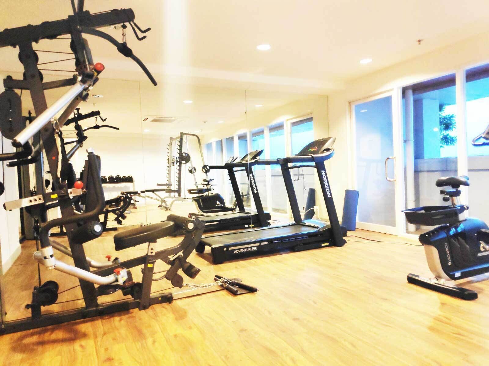 Un gimnasio con cintas de correr, bicicletas estáticas y equipamiento para levantamiento de pesas.