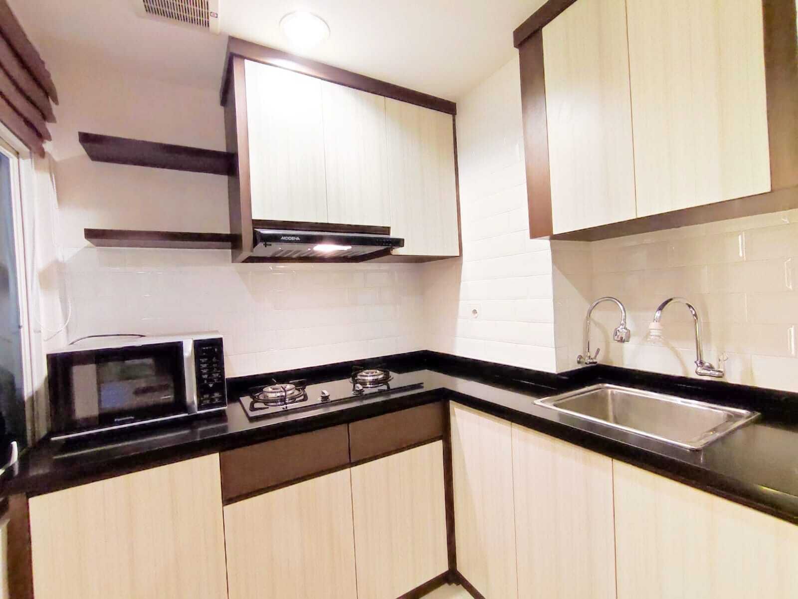 A compact kitchen with a microwave, stove, and sink.