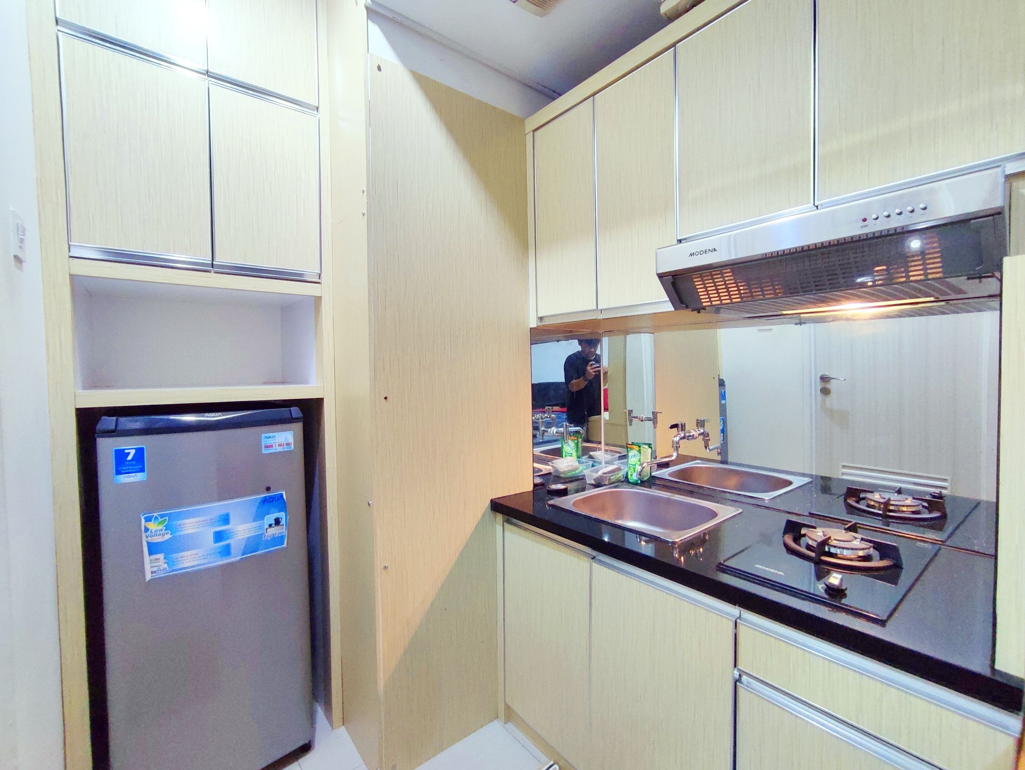 A compact kitchen with a refrigerator, double sink, and a stove.