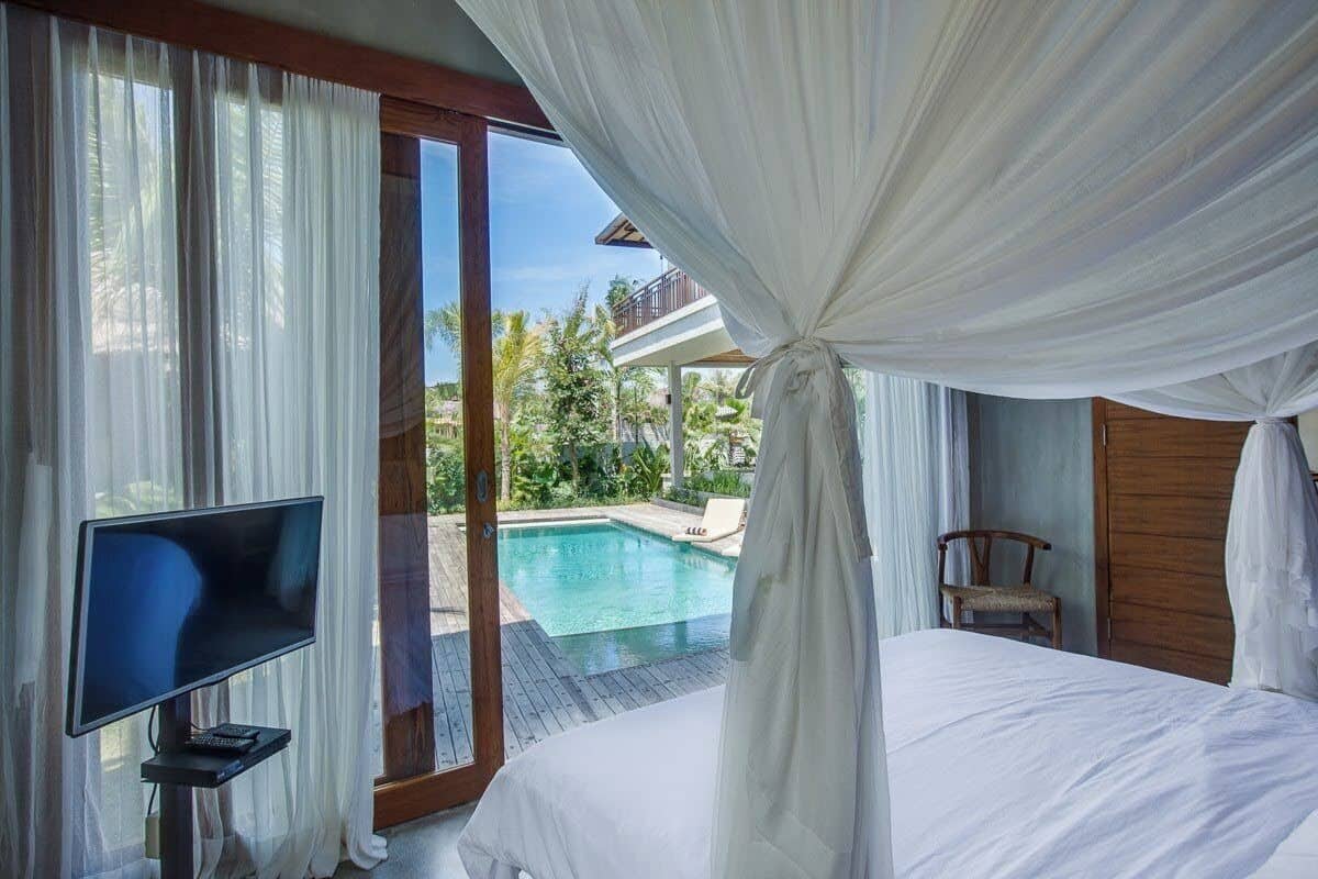 A bedroom with a large bed, a TV, and a view of a swimming pool.