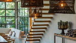 A modern interior with a staircase, wooden furniture, and a view of greenery outside. -  ZIN Berawa Villas & Bungalow (Tibubeneng)