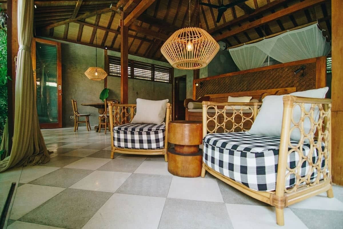 Ein Zimmer mit zwei Korbssofas, einem Holztisch und einer Hängeleuchte aus Rattan.