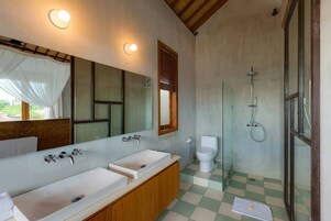 A bathroom with two sinks, a mirror, a toilet, and a shower.