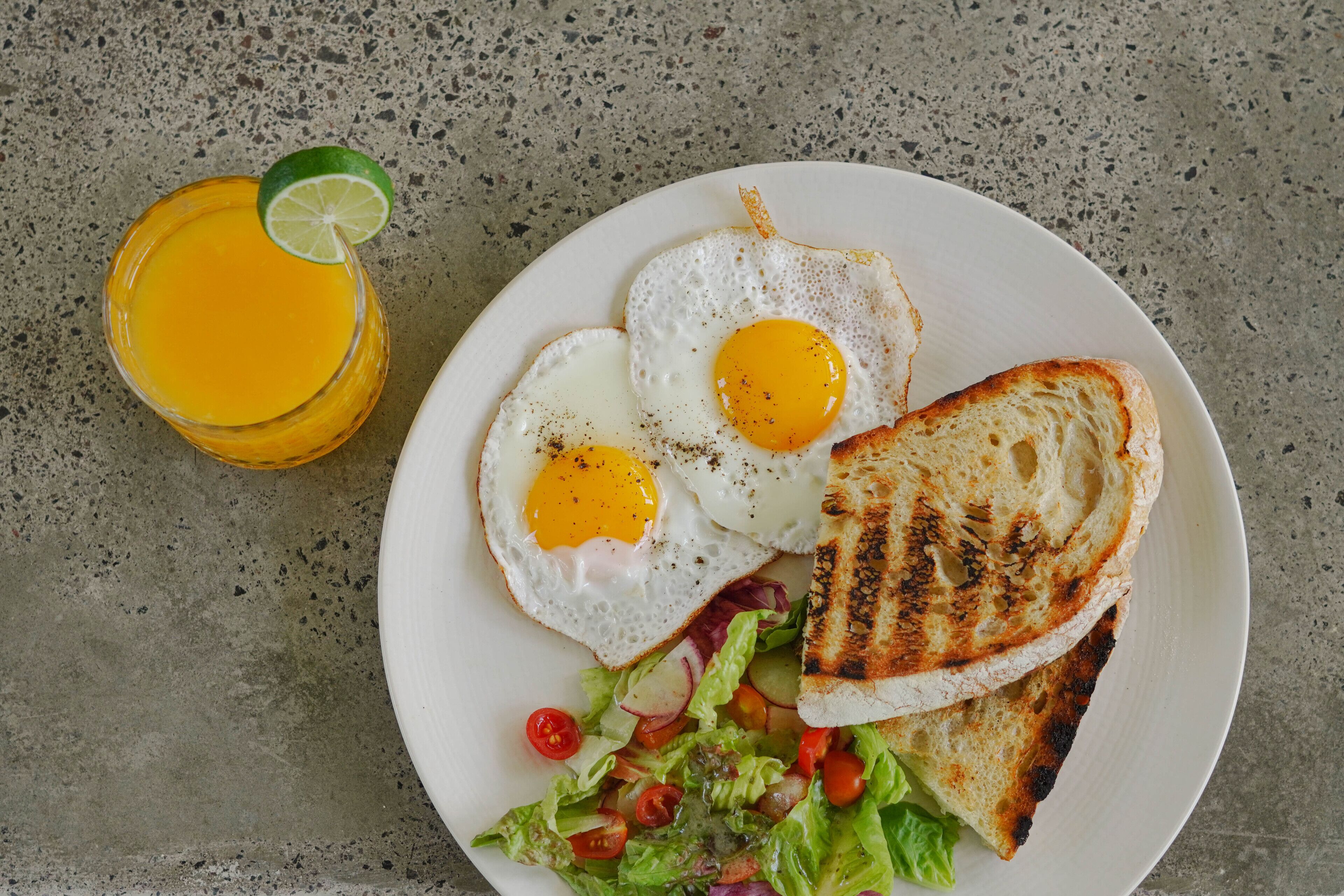 A plate with two sunny-side-up eggs, grilled toast, and a fresh salad with tomatoes and radishes.