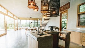 A modern kitchen with a central island, large windows, and a staircase leading to an upper level. -  ZIN Berawa Villas & Bungalow (Tibubeneng)