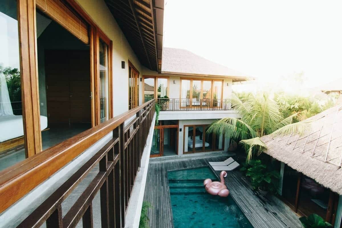 A pool area with a wooden deck, a lounge chair, and a flamingo float.