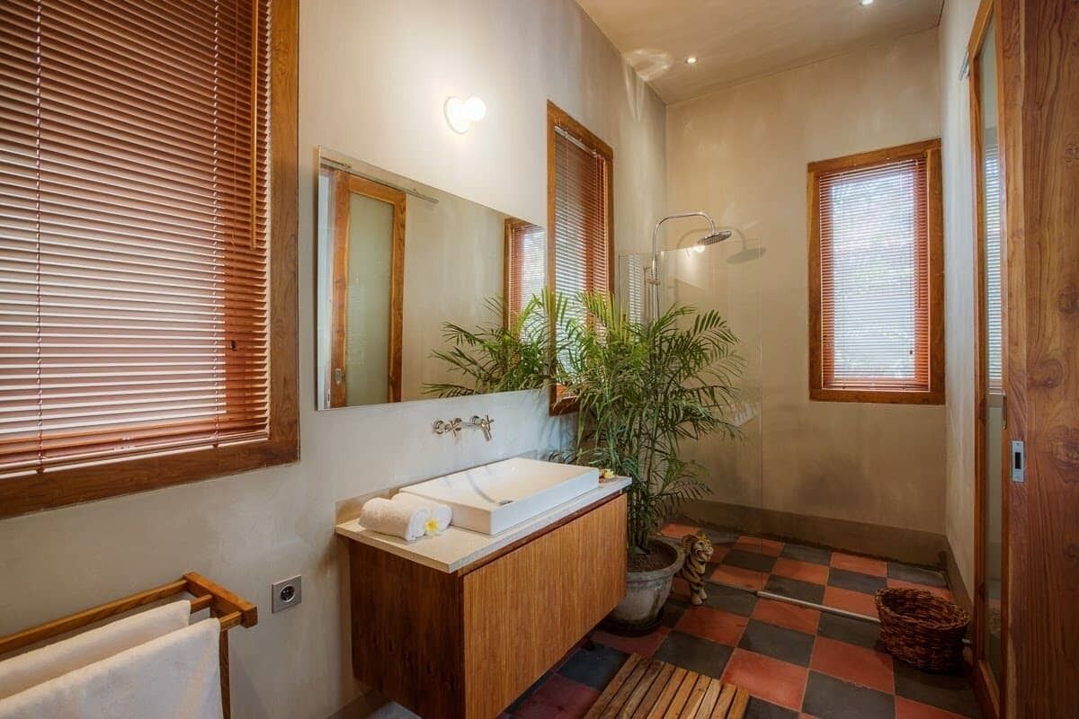 Ein Badezimmer mit einem Holzkosmetikschrank, einem großen Spiegel, einem Waschbecken und einer Dusche.