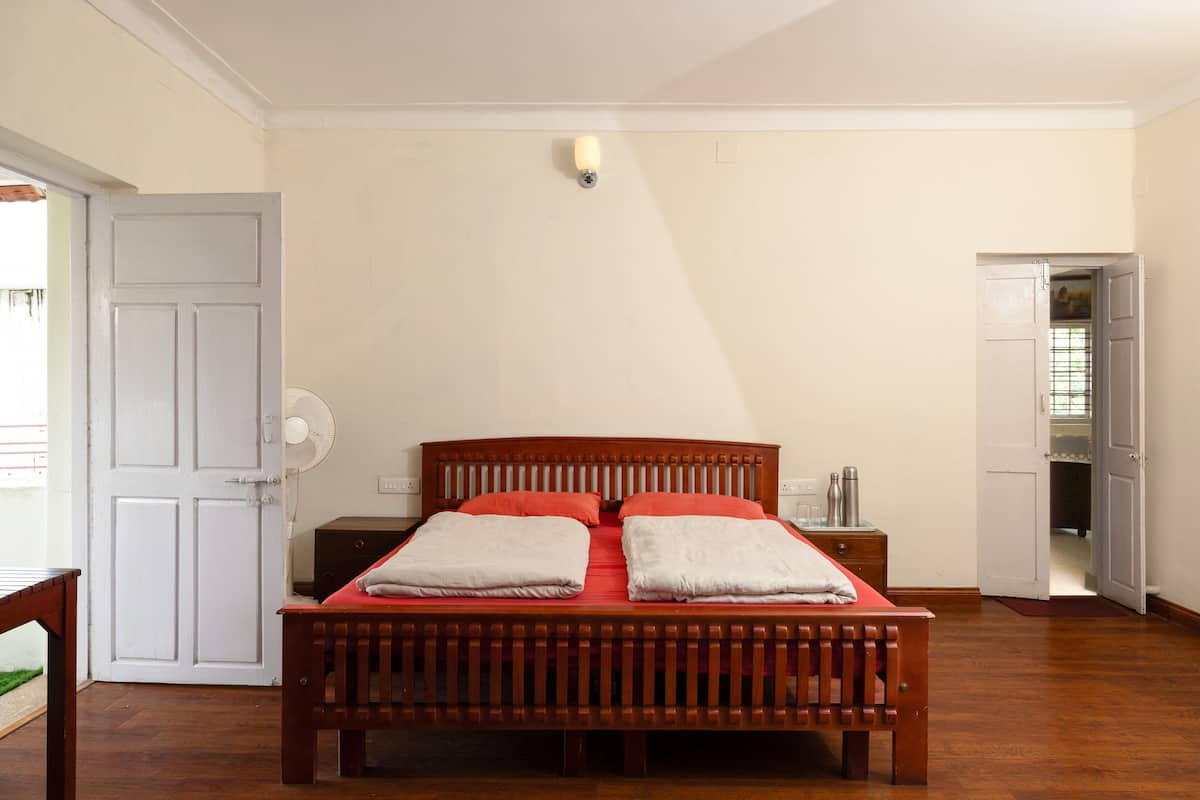 A bedroom with a wooden bed, white walls, and a door leading to another room.