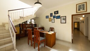 Una habitación amplia con una escalera, un escritorio con sillas y una estantería.