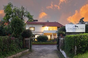 A hotel named 'Colonel's Inn' with a signboard, a paved entrance, and a well-maintained garden. - Colonel's Inn (Ootacamund)