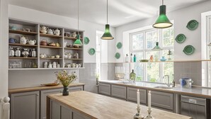 A kitchen with grey cabinets, a wooden countertop, and a variety of kitchenware on shelves. - Hotel Hornbækhus (Hornbaek)