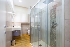 A modern bathroom with a glass-enclosed shower, a white sink, and a toilet.
