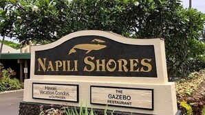 Señal de Napili Shores con un gráfico de delfín, indicando un condominio vacacional y el restaurante The Gazebo.