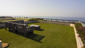 Une terrasse sur le toit offrant une vue sur l’océan, un espace salon et une rambarde.