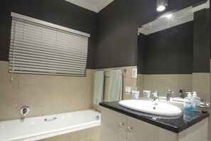 A modern bathroom with a bathtub, a sink, and a large mirror.