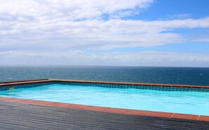 A swimming pool with a wooden deck and a view of the ocean. - 9 Sunrise Beach (Westbrook)