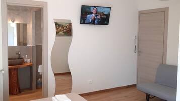 Una habitación de hotel moderna con cama, televisión, baño y suelo de madera.
