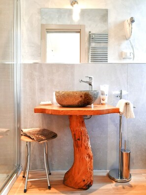 Un baño con un lavabo de madera grande, un espejo y un perchero para toallas.