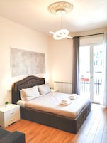 Un dormitorio moderno con una cama grande, una mesita de noche, un radiador y vistas al exterior.