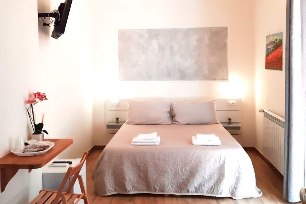 A modern bedroom with a large bed, a desk, and a chair.