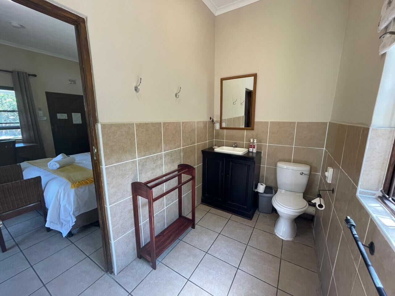 Ein Badezimmer mit einem Bett, einem Holzrahmen, einem schwarzen Schrank, einem Waschbecken und einer Toilette.