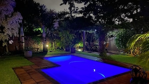 Un jardin avec une piscine, un espace patio et une clôture en bois.