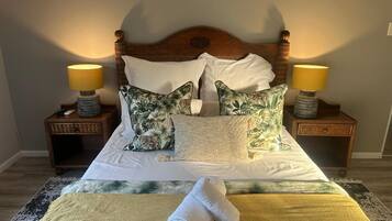 A neatly made bed with floral pillows, two bedside lamps, and a folded towel on the bed.