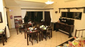 Un espace repas avec plusieurs tables dressées pour les repas, un téléviseur posé sur un meuble et un extincteur accroché au mur.