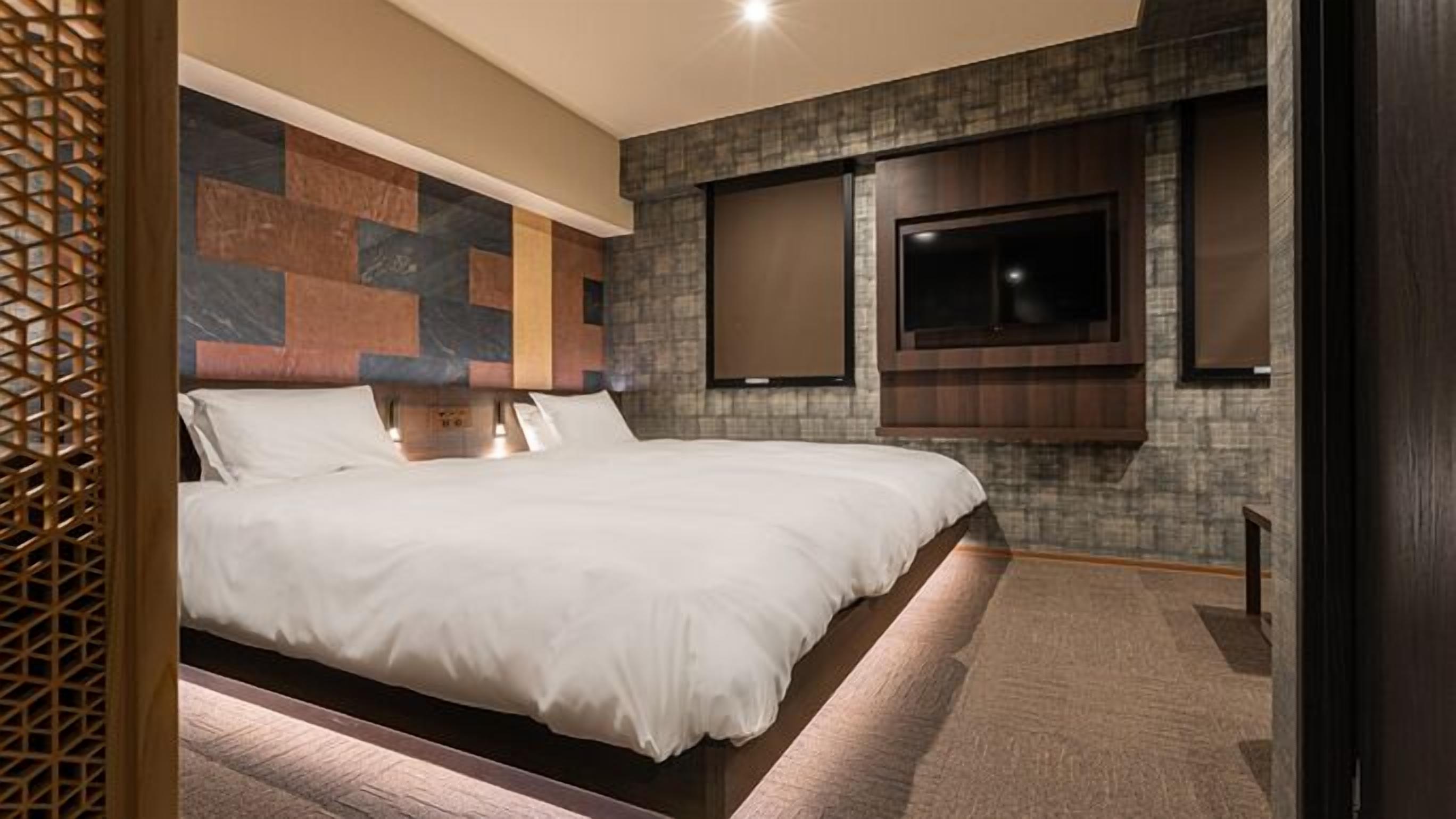 Una habitación de hotel moderna con una cama grande, un televisor de pantalla plana en la pared y un panel decorativo.