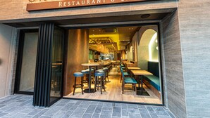 Ein Restaurantinnenraum mit Barbereich, Sitzgelegenheiten und einer sichtbaren Küche.
