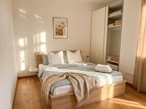 Un dormitorio con cama, mesita de noche, armario y un cuadro en la pared.