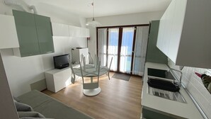 A modern kitchen with a built-in oven and a dining area with a glass table and chairs. - La Quiete 24 Holideal Apartment Lake view (Tremosine)