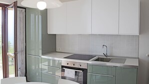 A modern kitchen with a built-in oven, a sink, and a dining area with a table and chairs. - La Quiete 24 Holideal Apartment Lake view (Tremosine)