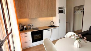 Une cuisine moderne avec des meubles en bois, un four à micro-ondes et un coin repas comprenant une table et des chaises blanches.