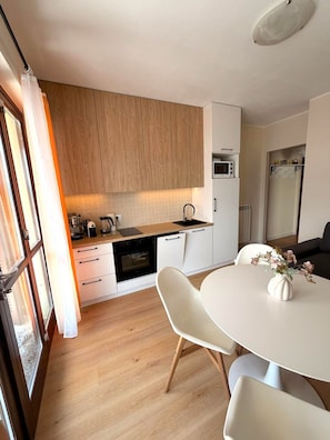 A modern kitchen with wooden cabinets, a microwave, and a dining area with a white table and chairs.
