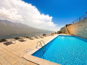 A swimming pool with a view of mountains, a stone wall, and a staircase leading to a terrace.