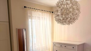 Une chambre à coucher comprenant un lit, une commode, un miroir et un luminaire au plafond original.