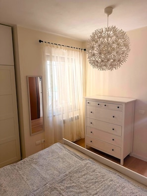 A bedroom with a bed, a dresser, a mirror, and a unique ceiling light fixture.