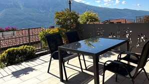 Une terrasse avec une table et des chaises, une lampe et une vue sur les montagnes.