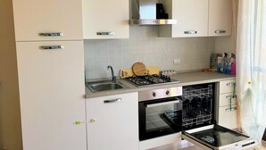 Une cuisine moderne avec des meubles blancs, des appareils en acier inoxydable, une cuisinière à gaz, un four et un lave-vaisselle.