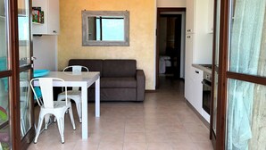 Un espace de vie compact comprenant un coin repas, un canapé et une kitchenette.