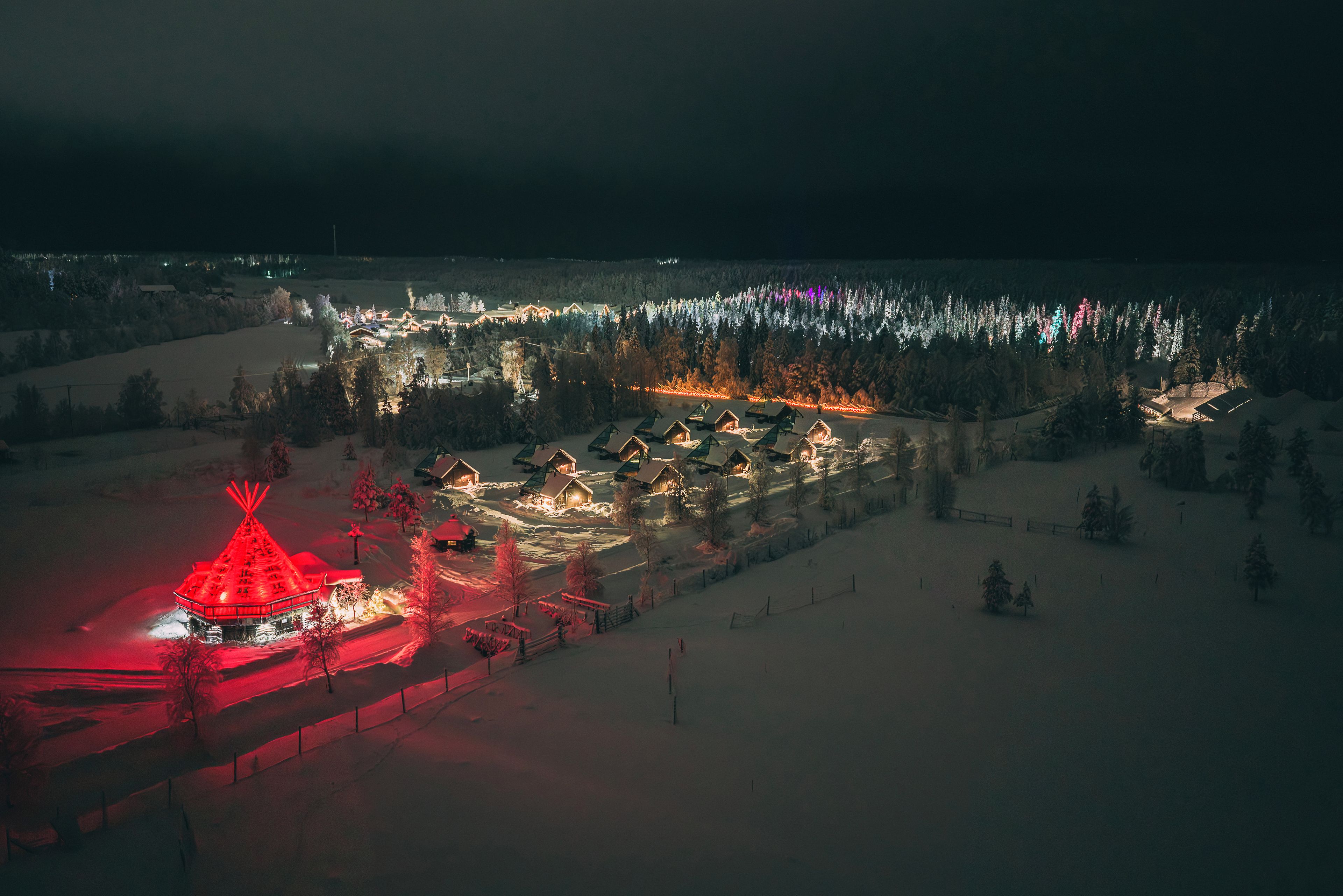 A snow-covered landscape with multiple cabins and a prominent red-roofed structure.