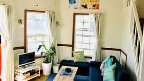 A living room with a TV, a coffee table, a sofa, and a potted plant. - Mini Chula Inn (Chatan)