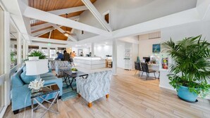 A spacious living area with a high ceiling, a kitchen in the background, and a large potted plant. - SUMMER SALE! Updated 1BR Unit with Pool and Hot Tub Sleeps 4 - Papakea  B201 (Lahaina)