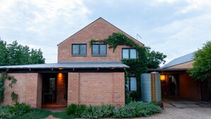 A brick house with a sloped roof, a covered porch, and a water tank. - Twin Rivers Bed and Breakfast (Centurion)