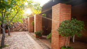A brick courtyard with a brick wall, potted plants, and a stone wall in the background. - Twin Rivers Bed and Breakfast (Centurion)