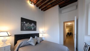 A bedroom with a large bed, two bedside lamps, a nightstand, and a framed picture on the wall. - Ripa 1 Apartment (Rome)
