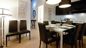 A dining area with a table set for six, surrounded by six chairs, a lamp, and artwork on the walls. - Ripa 1 Apartment (Rome)